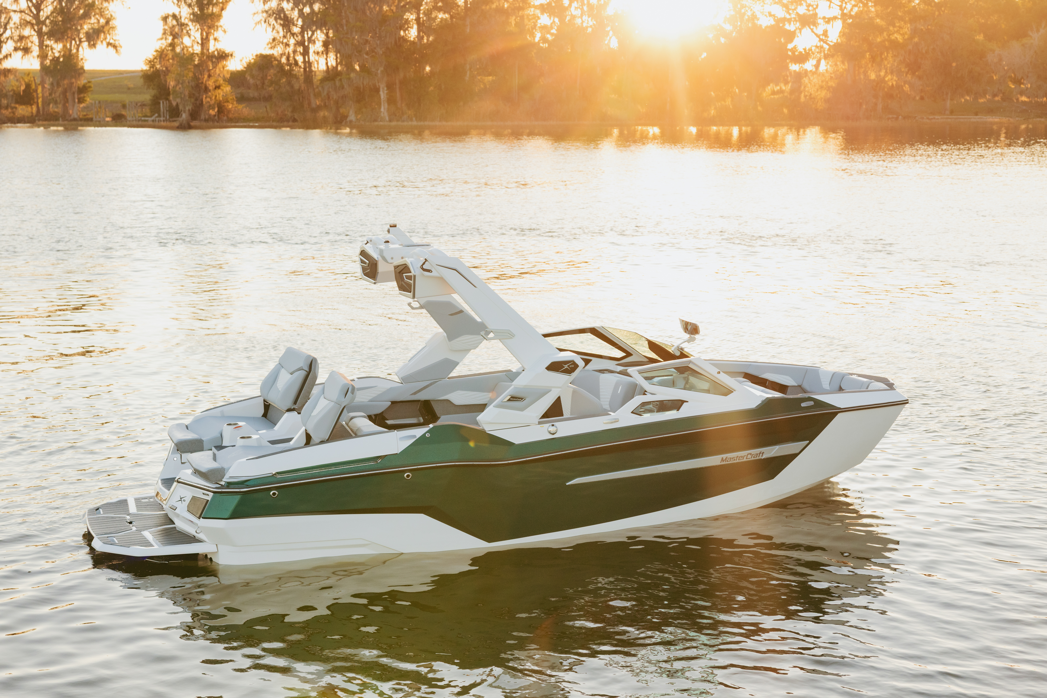 MasterCraft X23 floating on a lake during sunset.