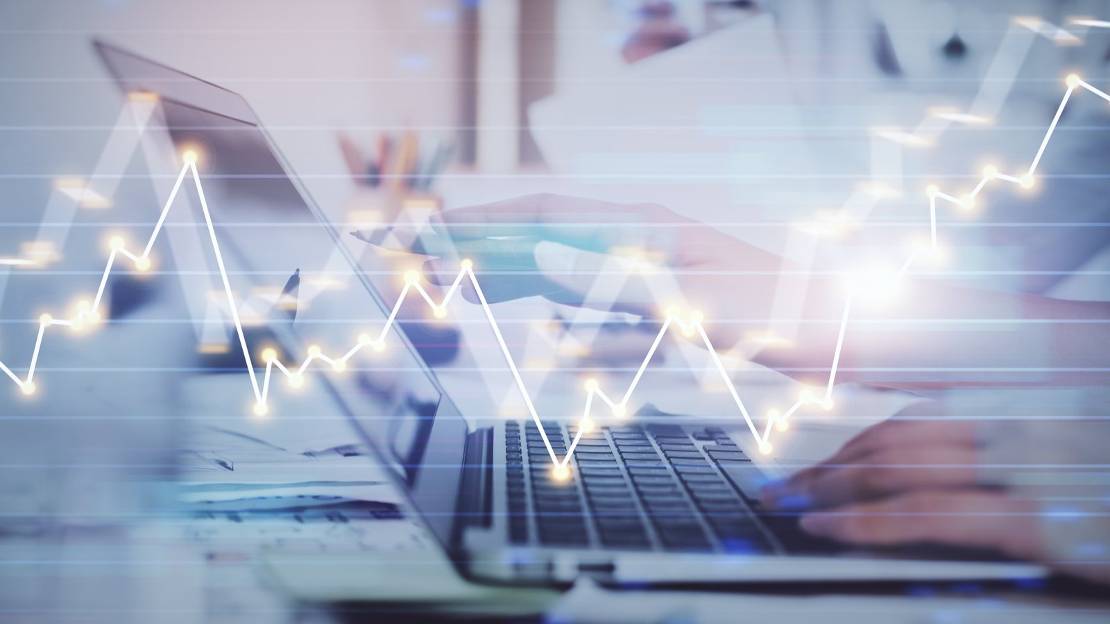 tech stocks A graphic of a person's hands resting on a laptop with a stock line graph moving through it