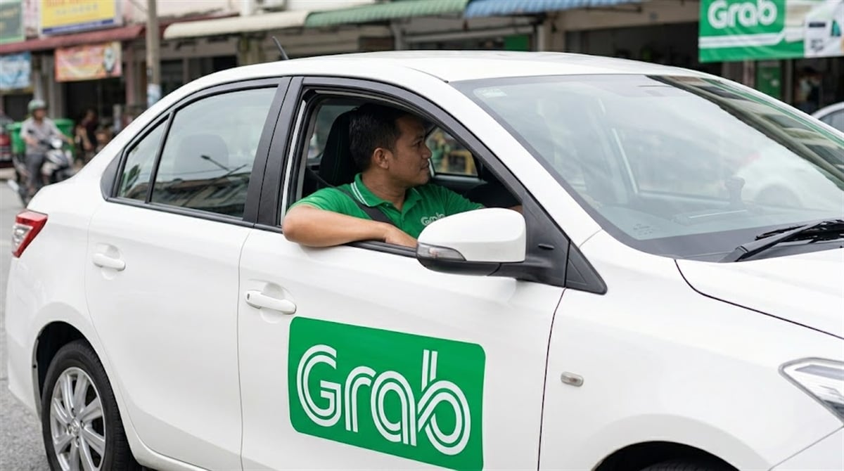 A Grab driver sits in a white sedan bearing the Grab logo on a city street.
