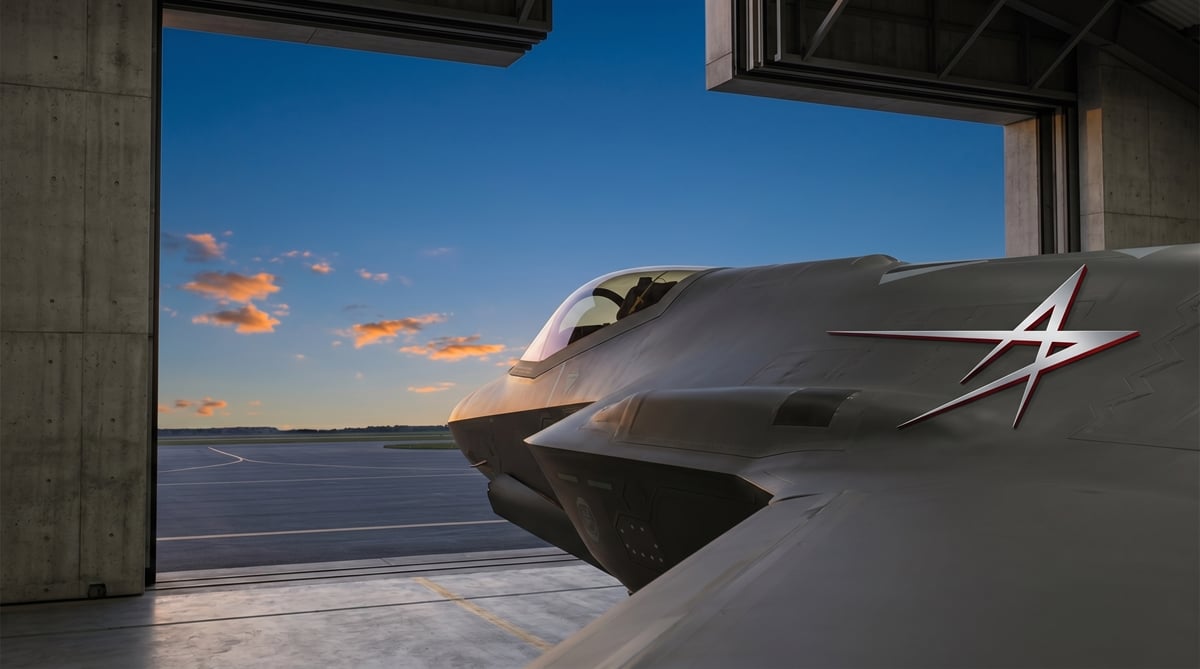 A Lockheed Martin F-35 fighter jet sits inside a hangar at dusk, bearing the company logo.