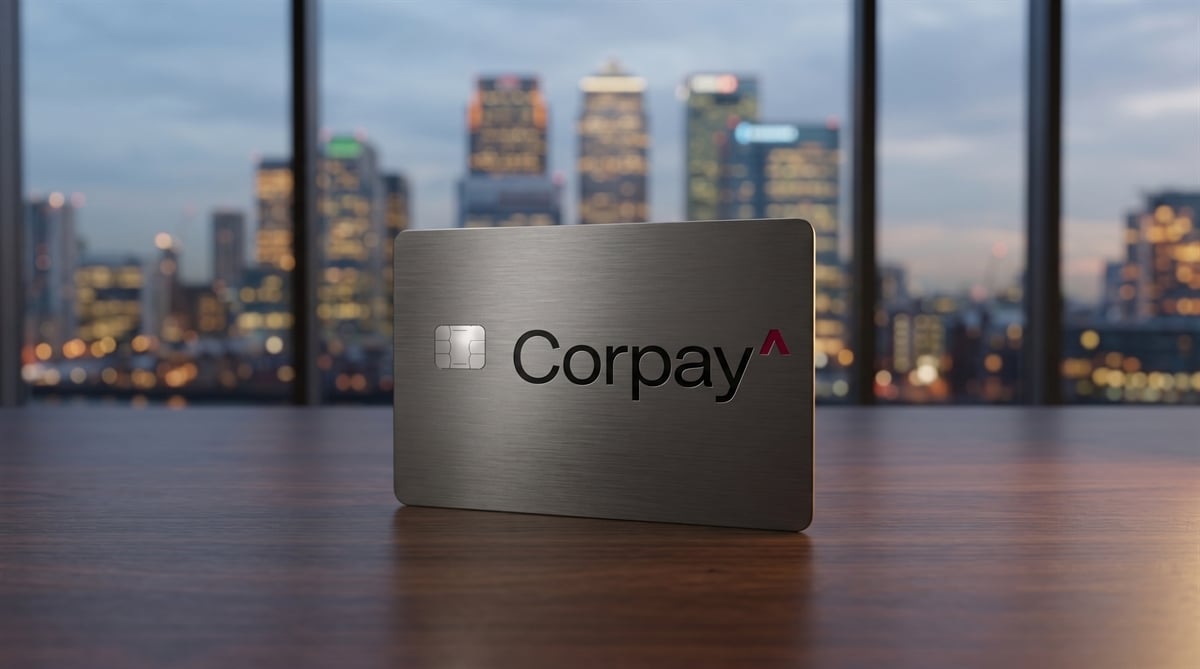 A metal Corpay-branded payment card stands upright on a wooden surface against a blurred city skyline backdrop.