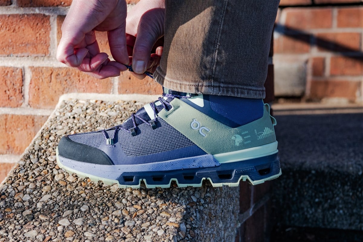 Woman laces up her On Cloud walking sneakers.
