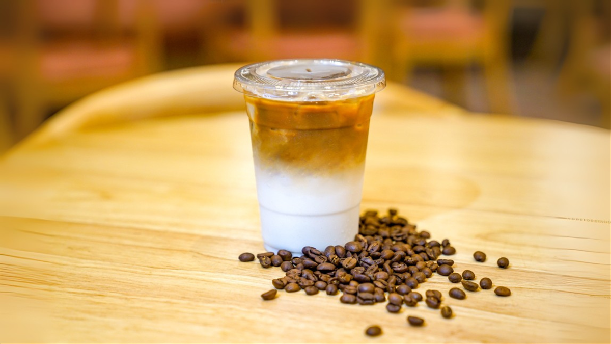 Take away Latte with Coffee bean around on the wood table — Photo