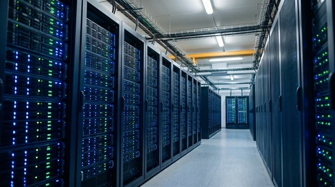 Rows of active server racks with blue and green indicator lights line a data center corridor.