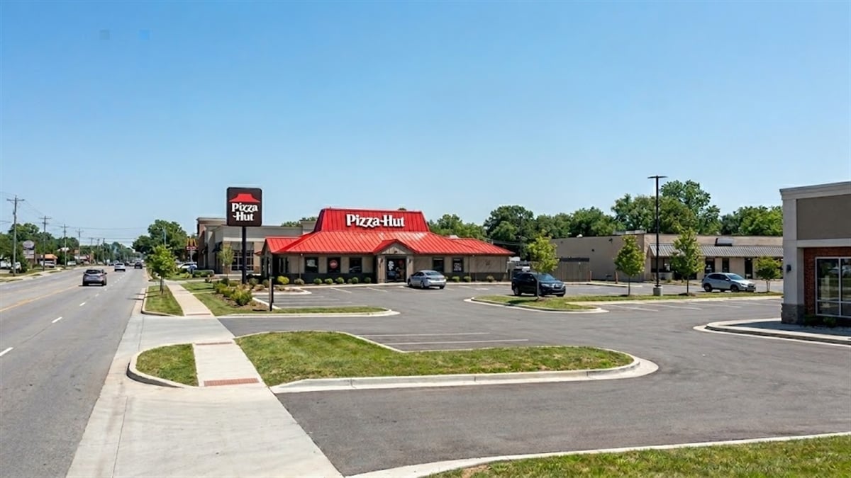 A Pizza Hut restaurant with a red roof and branded signage in a suburban strip mall parking lot.