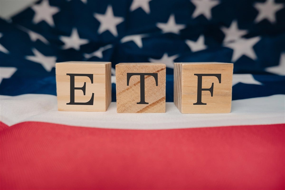 Wooden block with the letters ETF on it. The block is placed on top of a red and white American flag. The flag is spread out, and the ETF block is positioned in the middle of it — Photo
