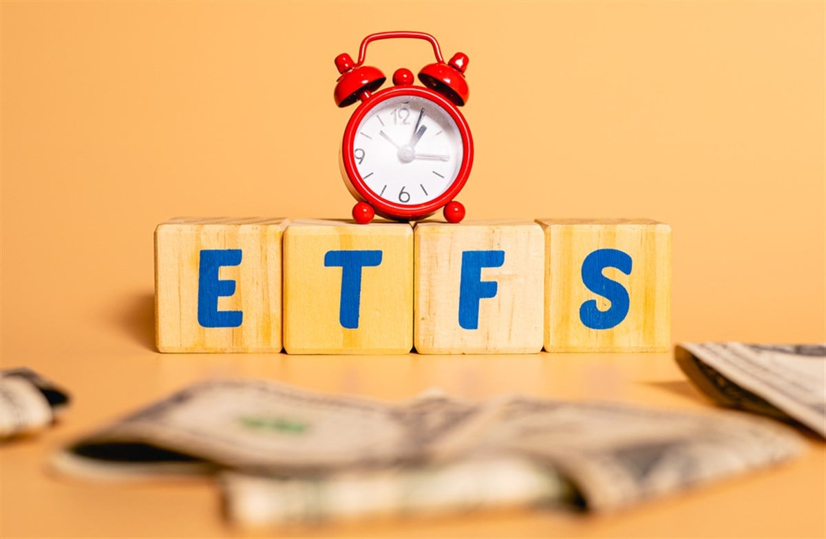The word ETFS written on wooden cubes on studio background. A money and a red clock in the image composition. — Photo