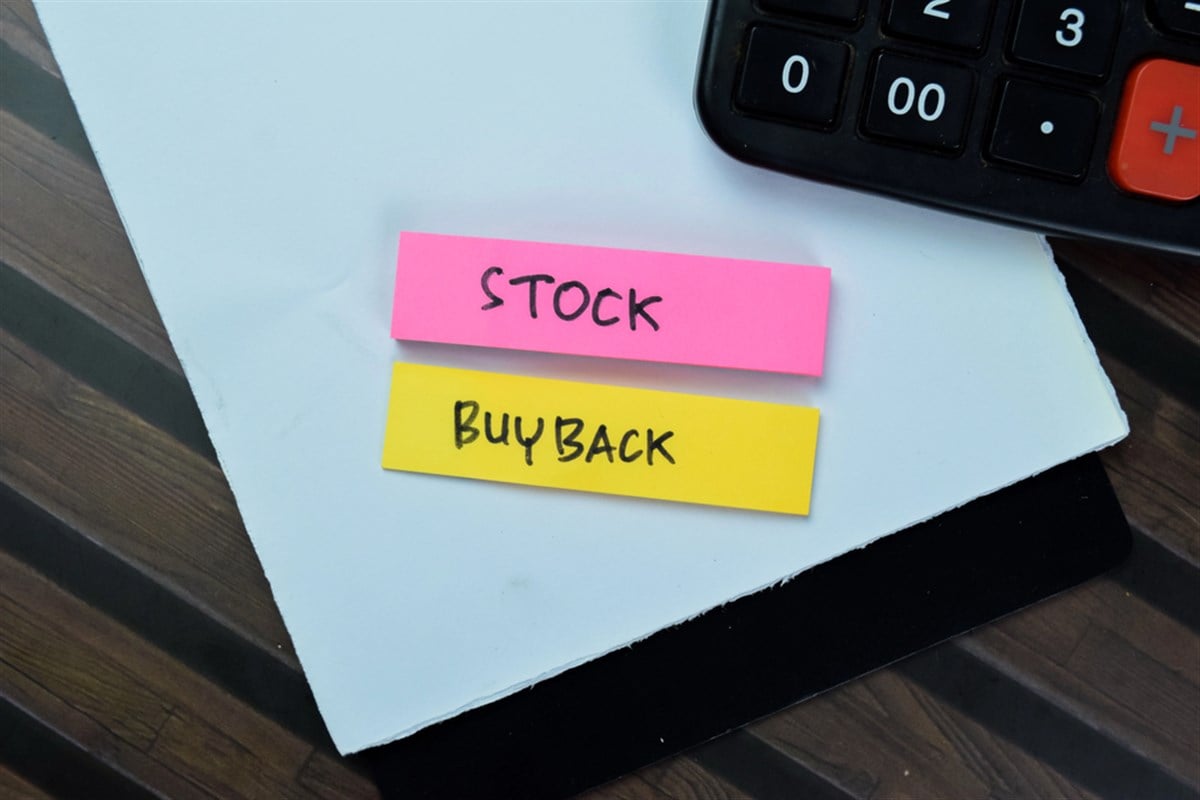 The words "stock buyback" on paper, with nearby calculator. 