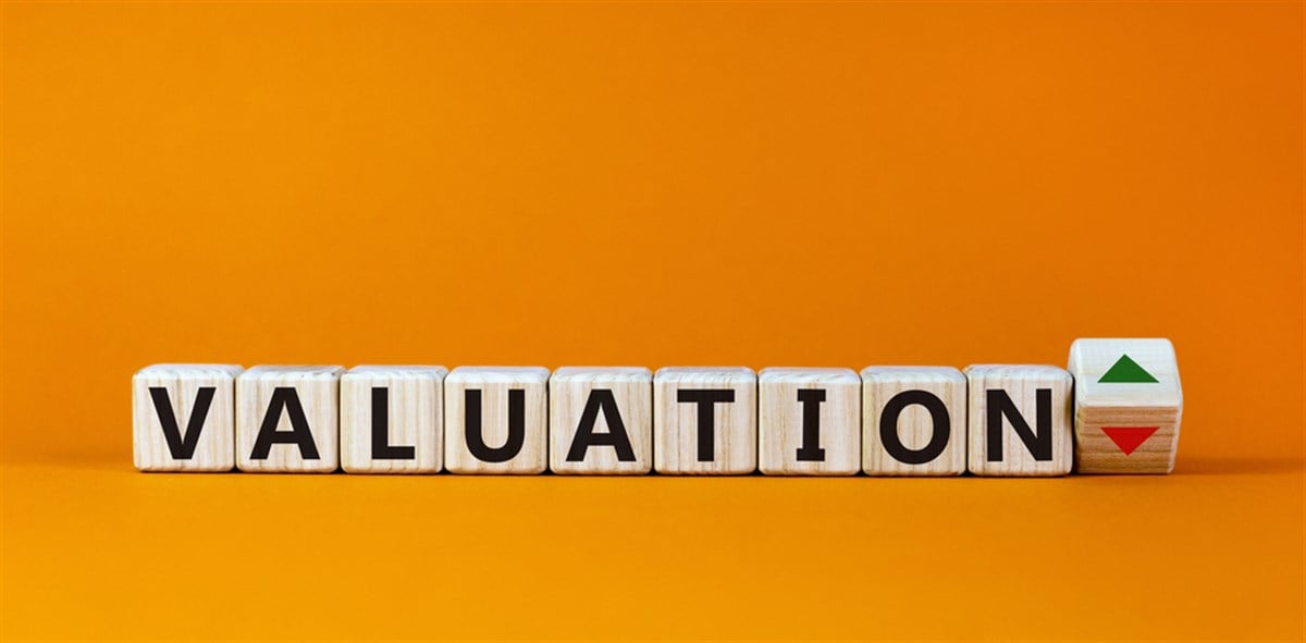 Valuation word on wooden cubes, up and down signs on orange background. Business concept, copy space.