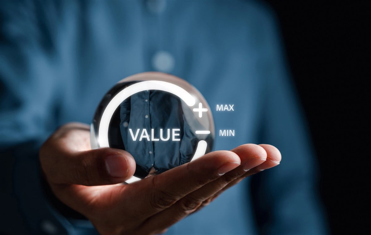 Photo of someone holding a hologram of the world "value" enclosed in a circle with plus and minus signs