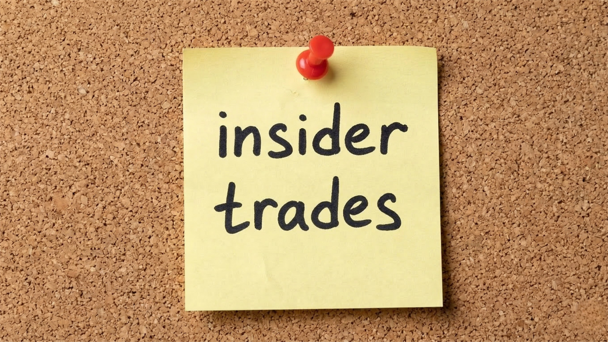 A yellow sticky note pinned to a corkboard reads “insider trades,” symbolizing insider selling activity in financial markets.