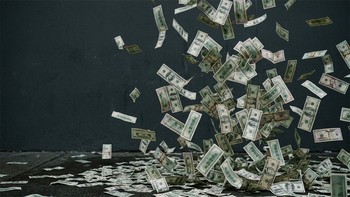 Falling US dollar bills scattered across a dark surface, symbolizing rising dividends and strong shareholder returns in financial markets.