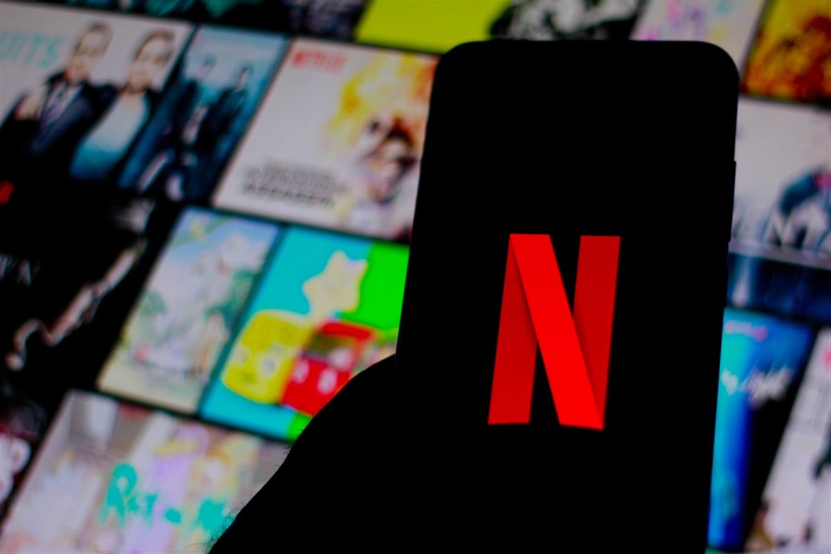 Mobile phone displays the Netflix logo in front a webpage displaying the company's media assets.