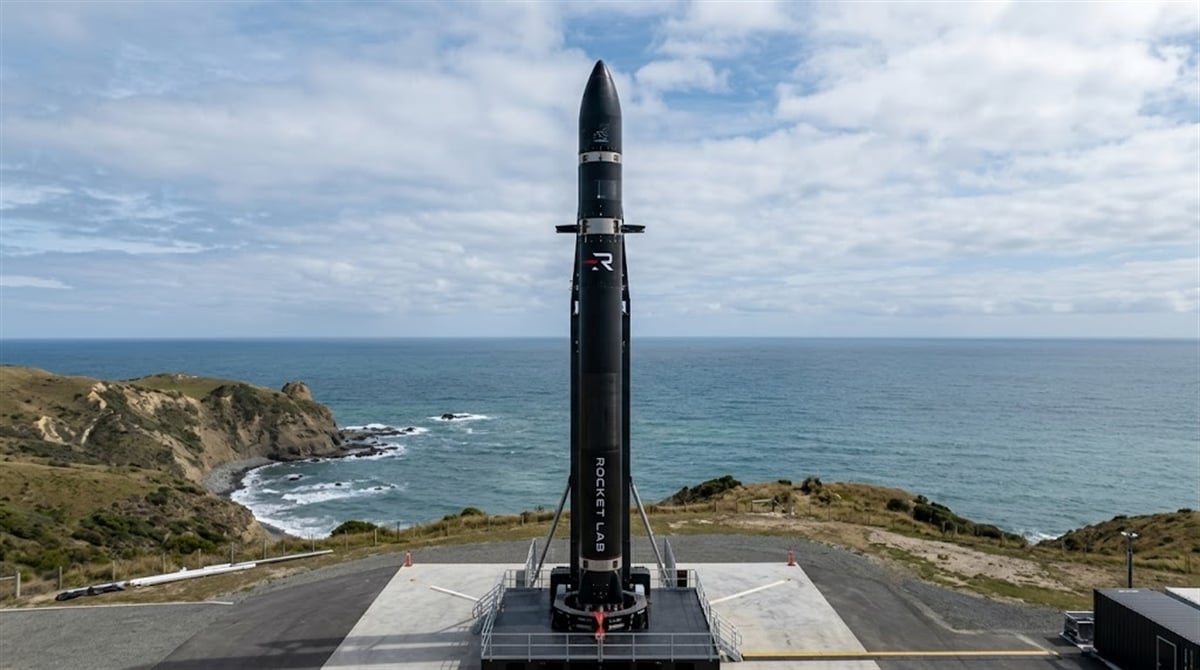 A Rocket Lab Electron rocket stands on a launch pad overlooking a coastal cliffside.