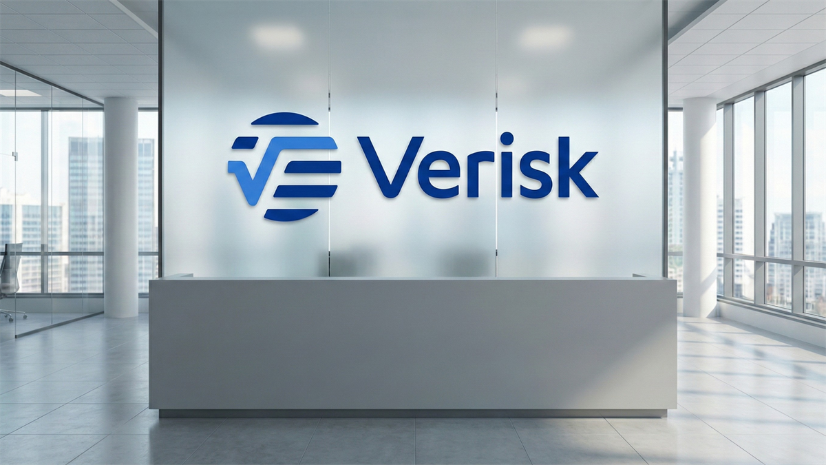 Verisk logo on a frosted-glass wall behind a modern reception desk in a bright office with city skyline views.