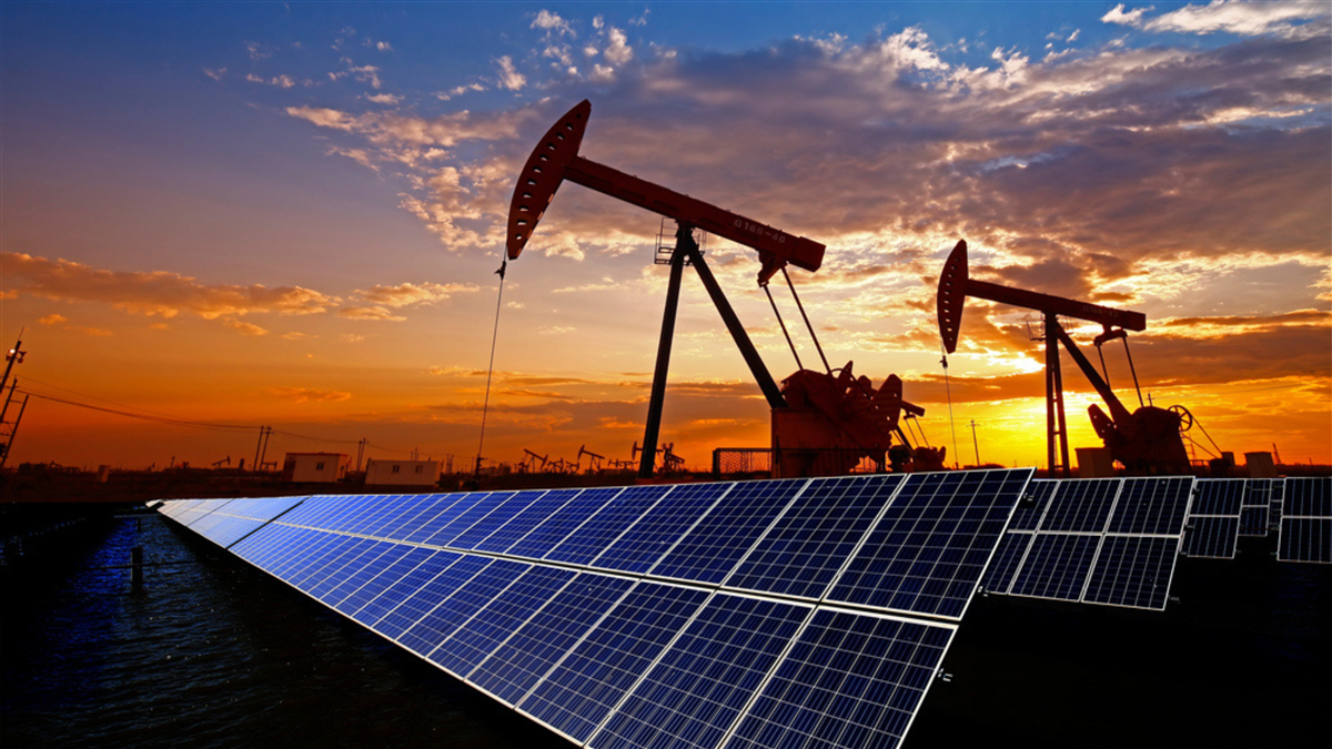 Oil pump jacks and solar panels at sunset.