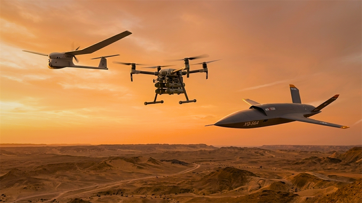 Three military-style drones fly over a desert at sunset.