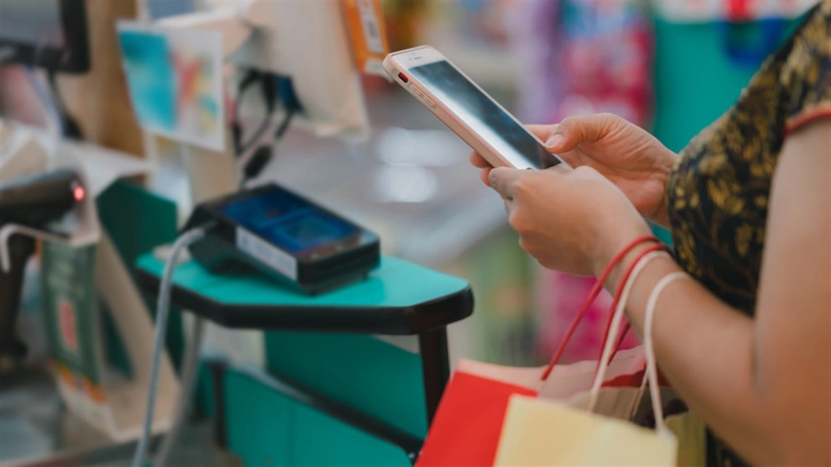 Shopper uses smartphone for payment at checkout counter, convenience of digital transactions in everyday shopping — Photo