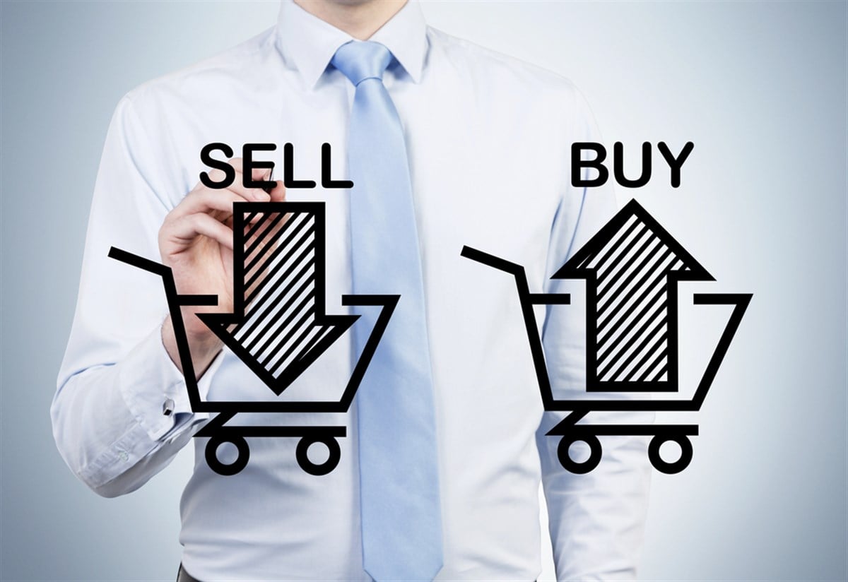 Businessman is drawing 'sell and buy' arrows on the glass screen. a concept of the trader who is forming a portfolio by selling and buying assets.