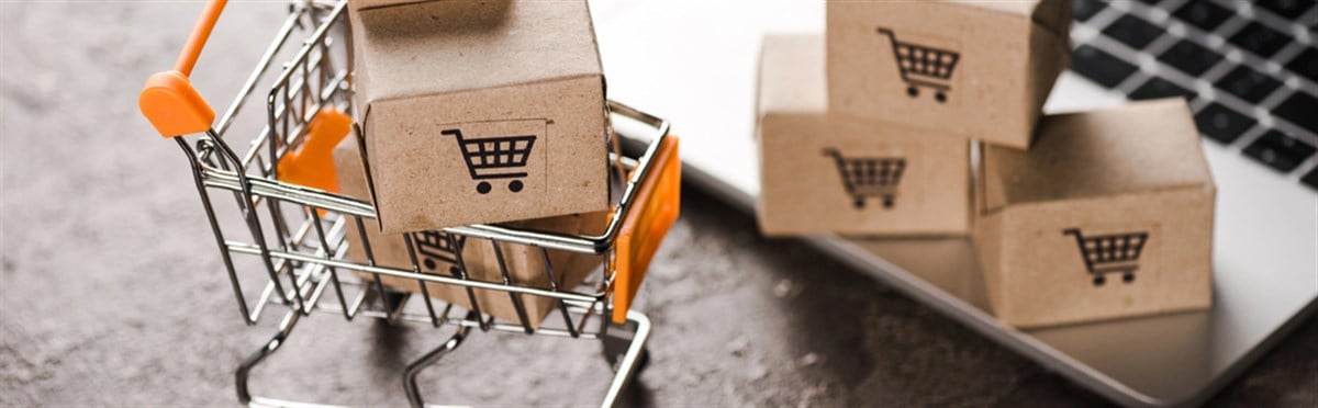 Panoramic shot of toy shopping cart with small carton boxes near laptop, e-commerce concept — Photo