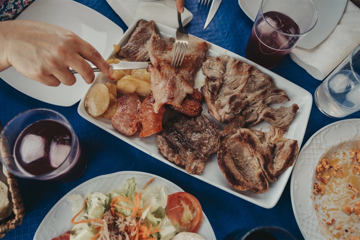 Restaurant table with blue tablecloth with food and alcoholic beverages. — Photo