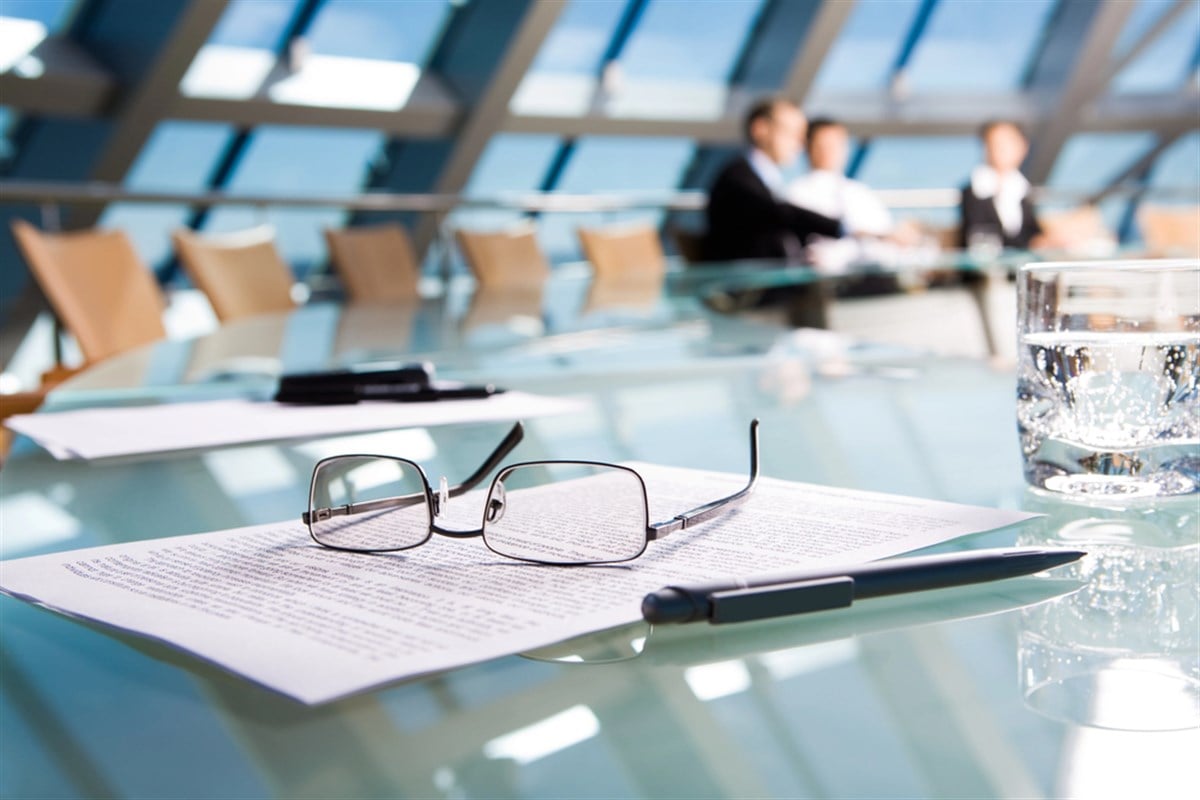 Glasses, documents, and a pen on a boardroom table reflect insider share sales shaping stock outlooks in late 2025.