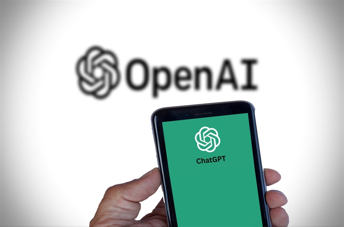 mobile phone ChatGPT on it, OpenAI logo in the background