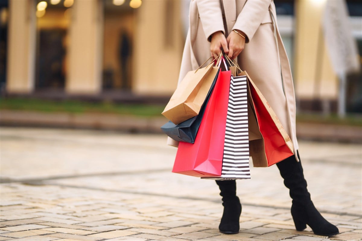 Woman holding an armful of shopping bags.