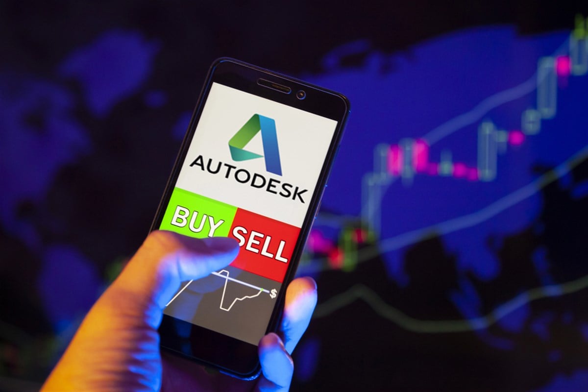 YESSENTUKI, RUSSIA - July 27, 2019: Company logo Autodesk, Inc. (ADSK) on smartphone screen, hand of trader holding mobile phone showing BUY or SELL on background of stock chart — Stock Editorial Photography