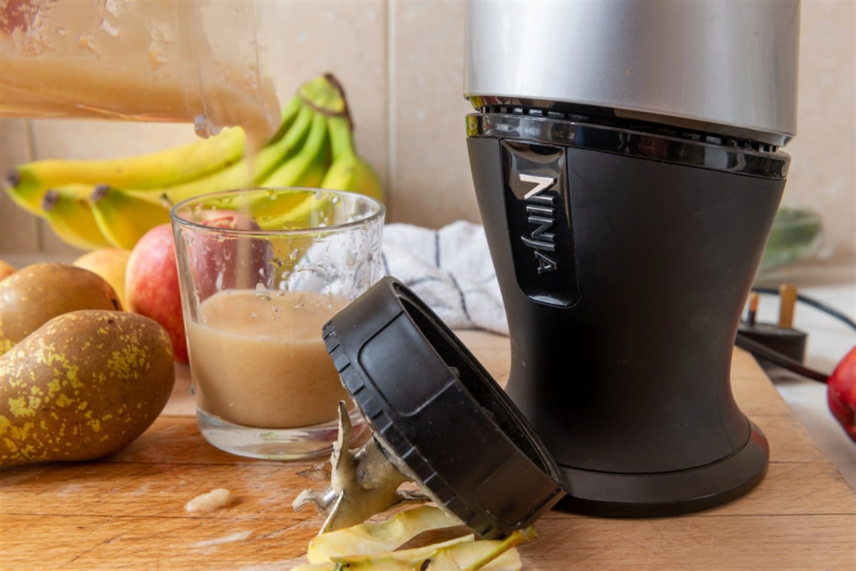 a ninja juicer with a person holding a glass of blended juice