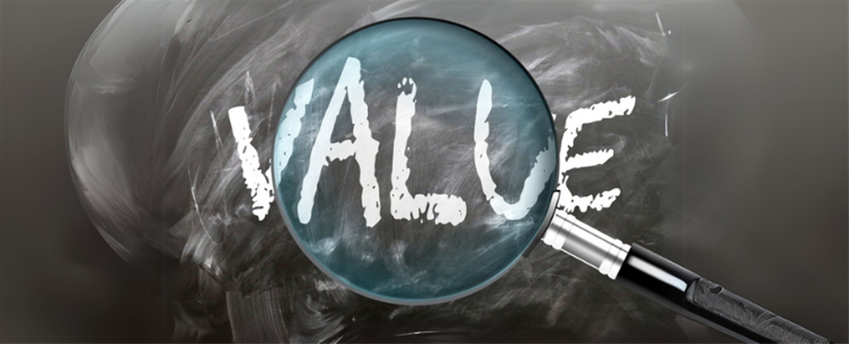 Photo of the word VALUE written on a black chalkboard with a magnifying glass over the word.