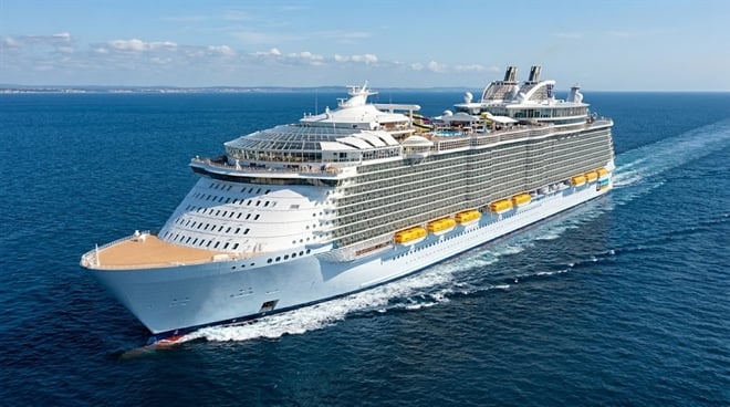 A large Royal Caribbean cruise ship sails through open blue ocean waters.