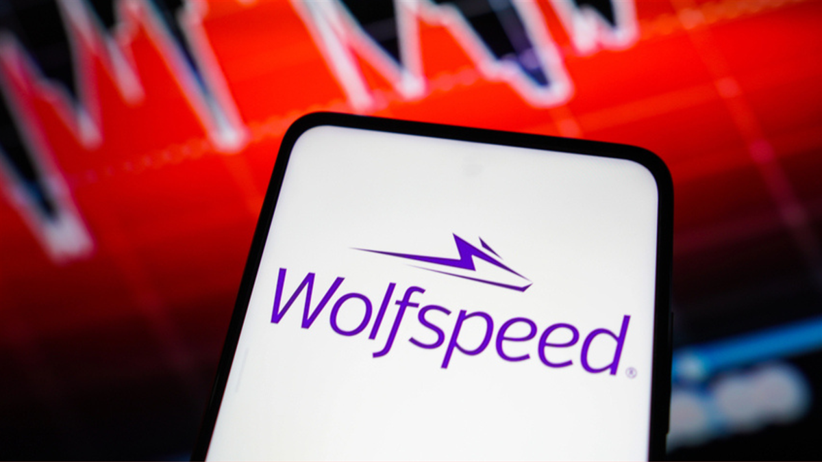 Wolfspeed logo appears against a falling stock chart backdrop as the company strengthens its balance sheet with new IRS funding.