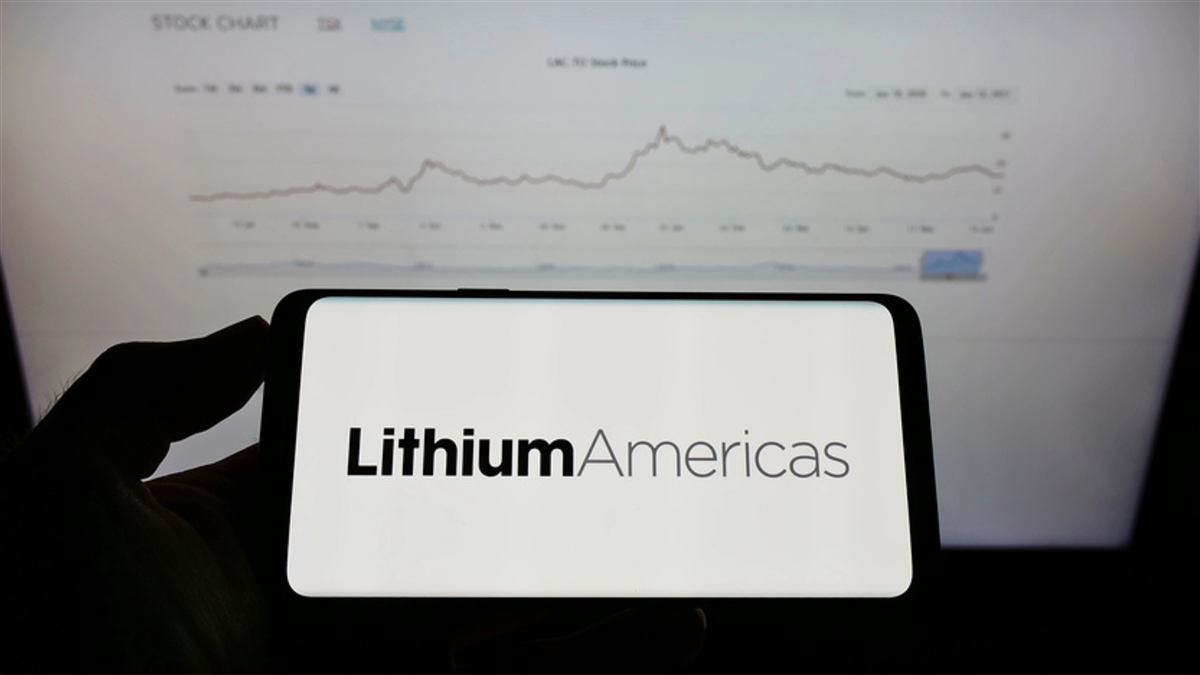 Person holding mobile phone with logo of Canadian company Lithium Americas Corp. on screen in front of business web page. Focus on phone display.
