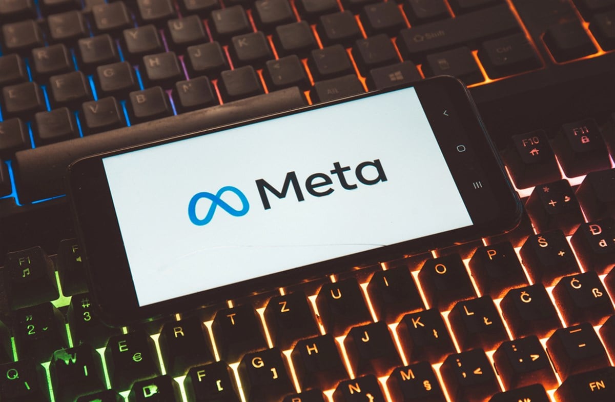 Meta logo displayed in front of luminescent computer keyboard.