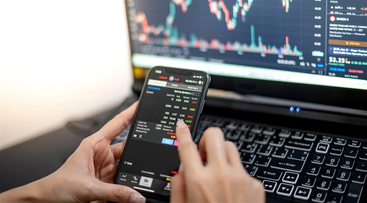 Female trader investor broker analyst holding smartphone in hand analyzing stock market trading charts indexes data checking price using mobile stockmarket exchange app while the World economis still recession. — Photo