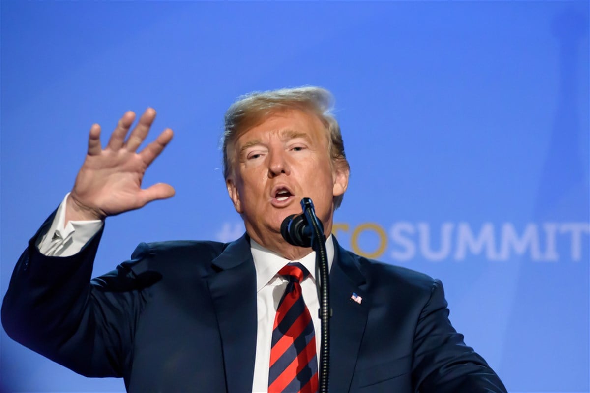 President Donald Trump gestures while addressing a crowd.