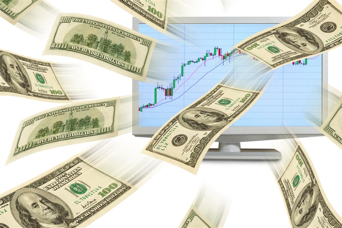 Cash dollars fly out of a computer monitor with the exchange schedule.