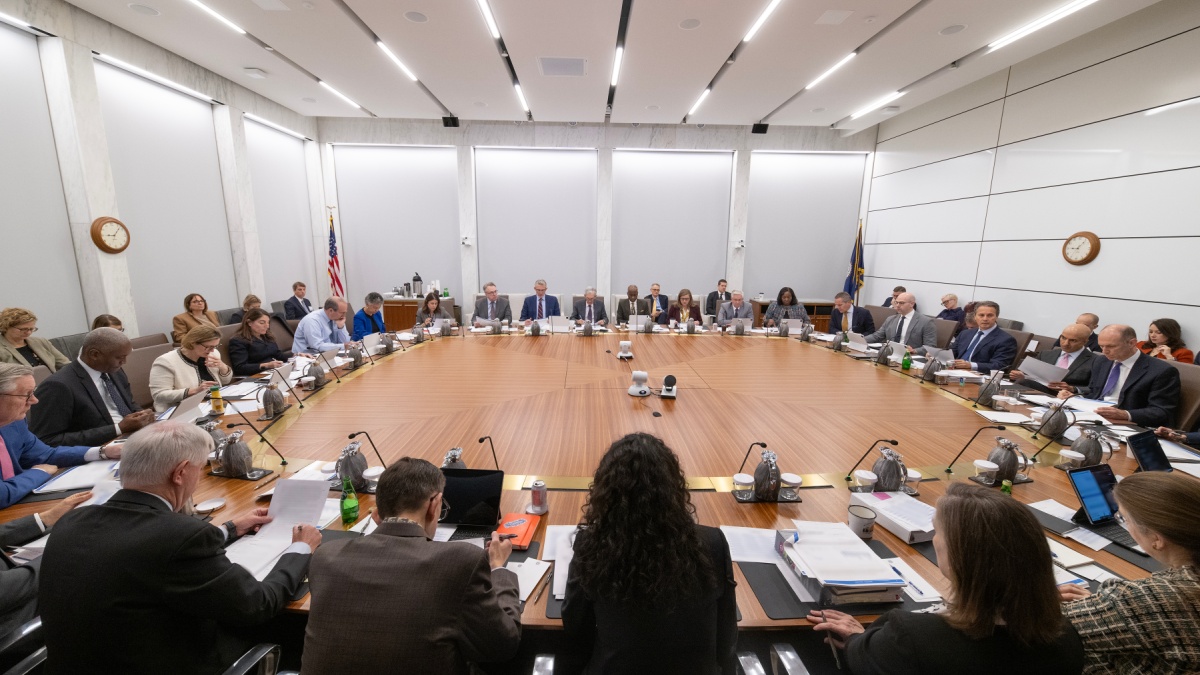 Federal Reserve board members sit around table at meeting.
