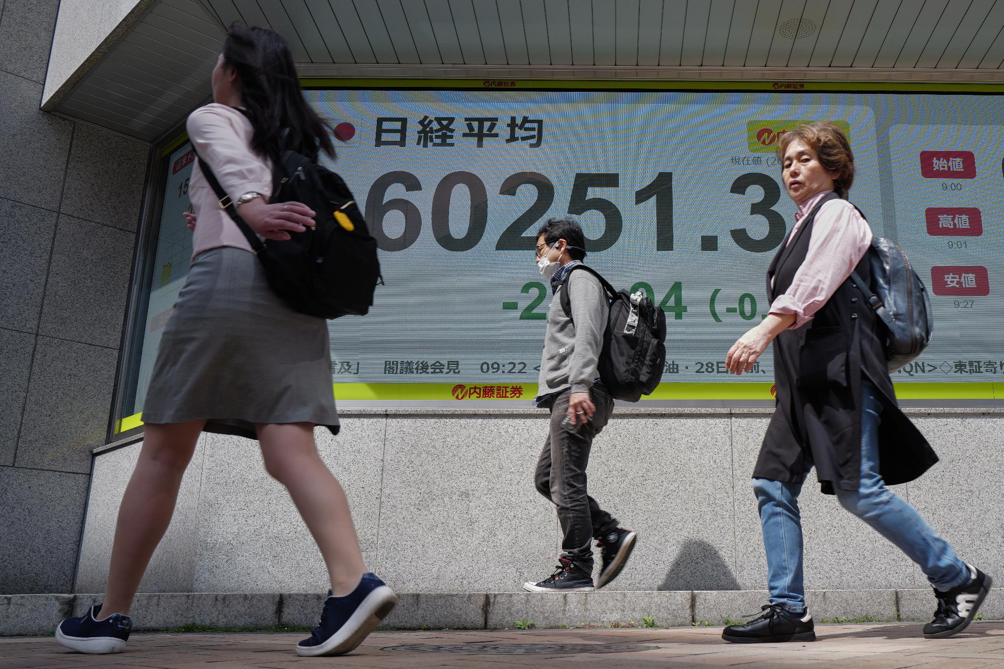 People past an electronic stock board showing Japan's Nikkei index at a securities firm Tuesday, April 28, 2026, in Tokyo. (AP Photo/Eugene Hoshiko)