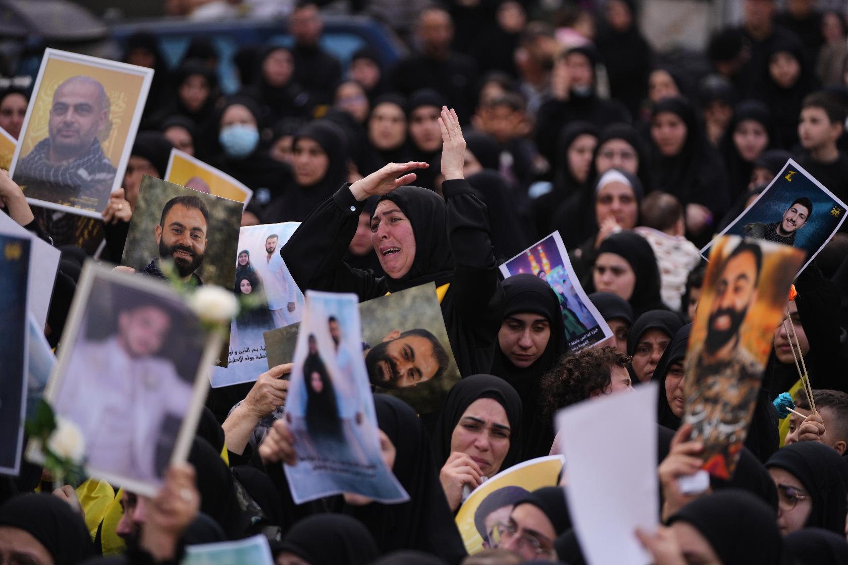 A woman mourns as other hold portraits of Hezbollah fighters, who were killed before the ceasefire in the war between Hezbollah and Israel, during a mass funeral procession in the southern village of Kfar Sir, Lebanon, Tuesday, April 21, 2026. (AP Photo/Hassan Ammar)