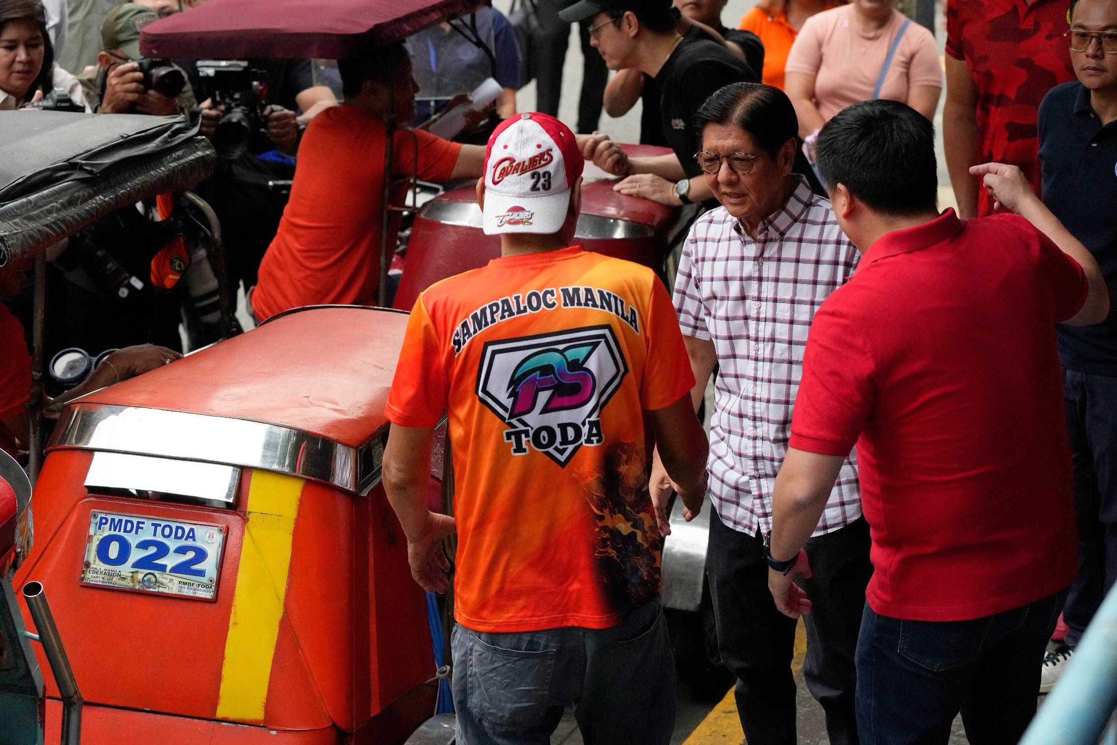 Philippine President Ferdinand Marcos Jr., talks to a tricycle driver as he visits a cash relief assistance center to help drivers in their livelihood as oil prices continue to rise on Tuesday, March 17, 2026, in Manila, Philippines. (AP Photo/Aaron Favila)
