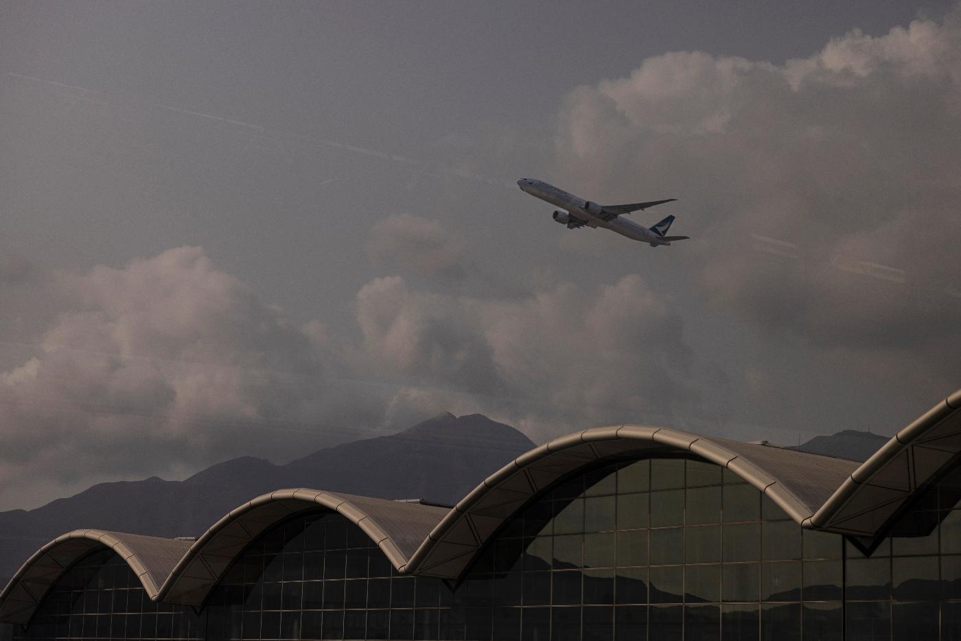 An aircraft operated by Cathay Pacific Airways is seen through glass as it takes off from Hong Kong International Airport in Hong Kong, on Wednesday, March. 8, 2023. Cathay Pacific Airways Ltd. said it was ready to rebuild as Hong Kong opened up to global visitors, despite reporting wider losses in 2022. (AP Photo/Louise Delmotte)