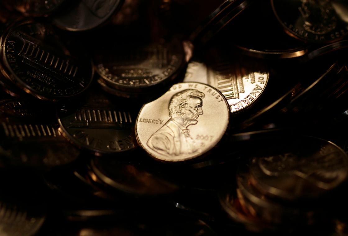 FILE - A lone penny is illuminated in a bin of completed pennies at the U.S. Mint in Denver on Wednesday, Aug. 15, 2007. (AP Photo/David Zalubowski, File)