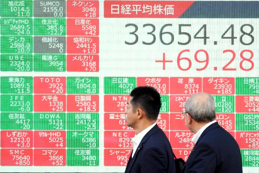 People walk past an electronic stock board showing Japan's Nikkei 225 index at a securities firm Monday, Nov. 20, 2023, in Tokyo. Asian shares were higher Monday after Wall Street closed its third straight winning week with a tiny gain. (AP Photo/Eugene Hoshiko)