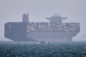A container ship sits at anchor as a small motorboat passes in the foreground in the Strait of Hormuz off Bandar Abbas, Iran, Saturday, May 2, 2026. (Amirhosein Khorgooi/ISNA via AP)