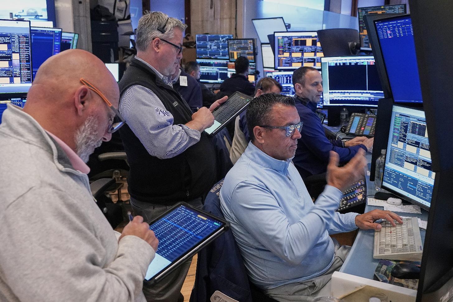 Robert Finnerty, Jr., foreground right, works with colleagues on the floor of the New York Stock Exchange, Thursday, May 7, 2026. (AP Photo/Richard Drew)