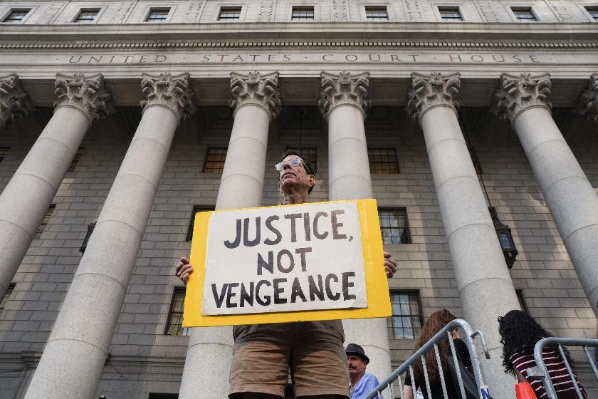 A man holds a sign outside of Manhattan Federal Court on the day of a hearing for Luigi Mangione on Friday, Aug. 14, 2026, in New York. (AP Photo/Ryan Murphy)
