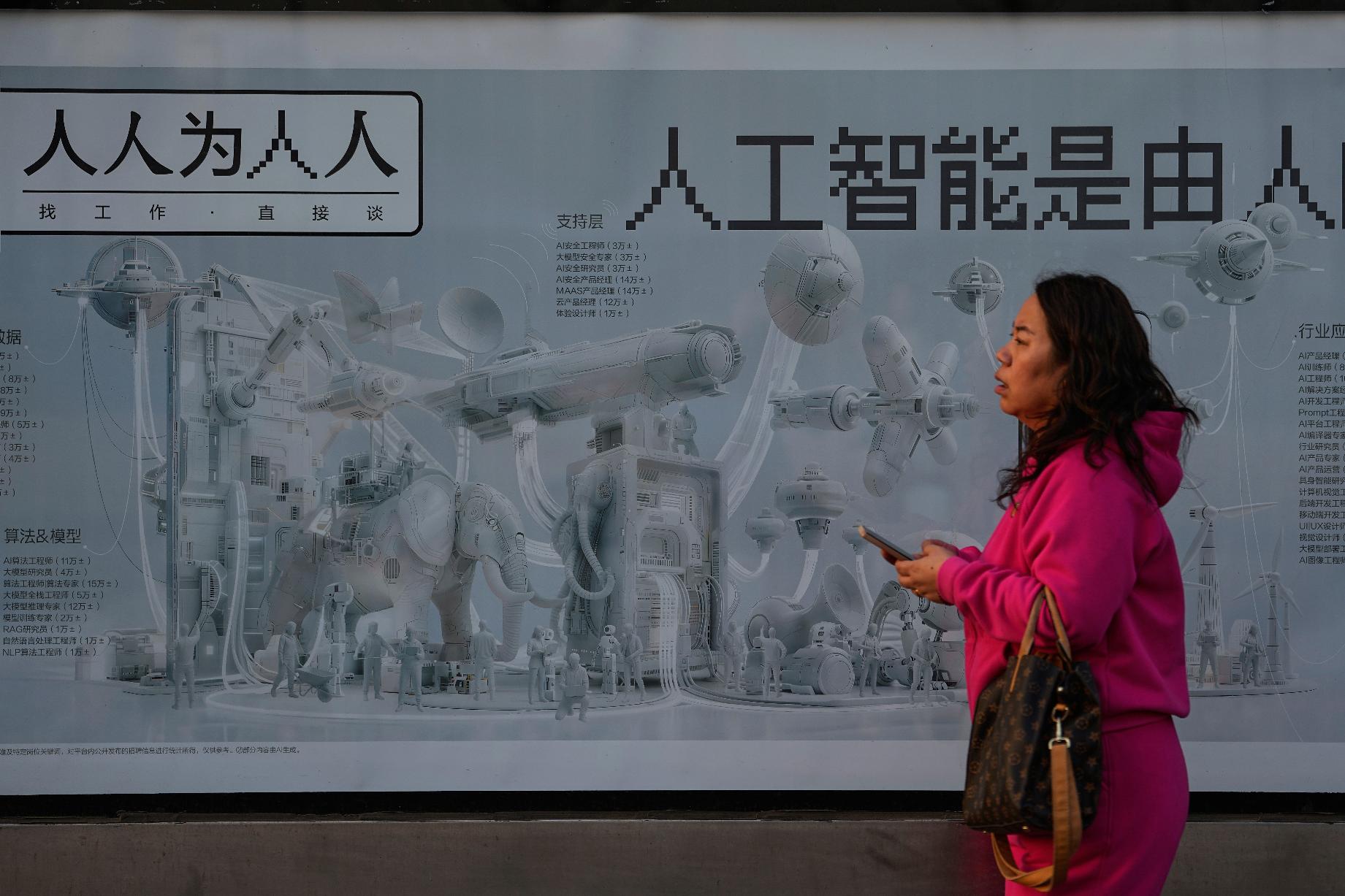 A woman walks past a job hunting advertisement poster carrying the words "Artificial intelligence is brought by human work" at a bus stand, in Beijing on Sunday, March 8, 2026. (AP Photo/Andy Wong)