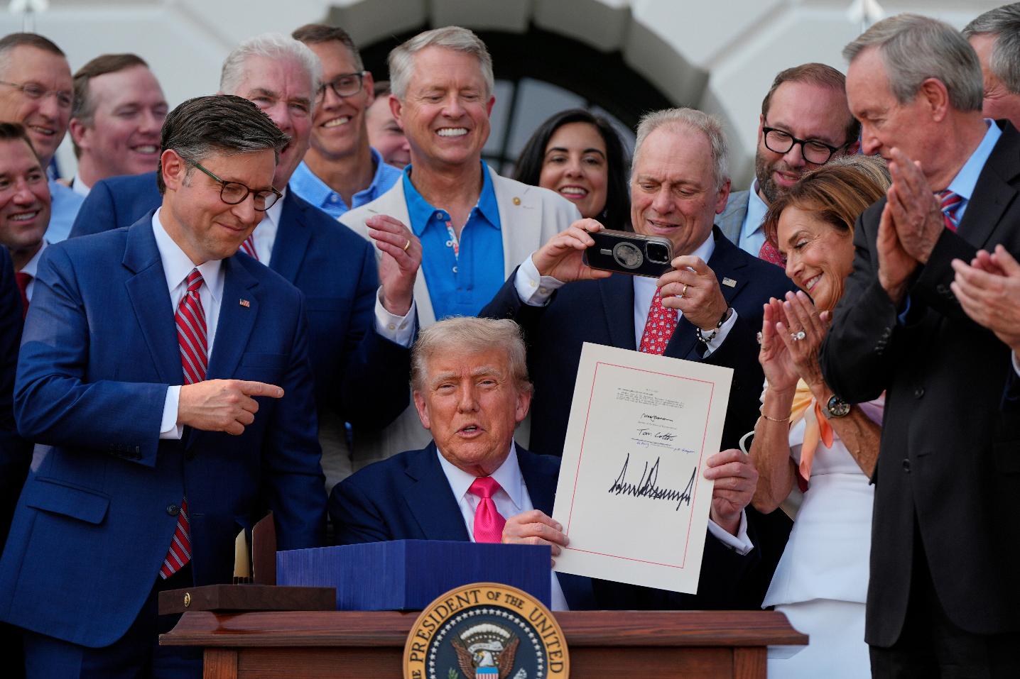 FILE - President Donald Trump holds his signed signature bill of tax breaks and spending cuts at the White House, July 4, 2025, in Washington, surrounded by members of Congress. (AP Photo/Julia Demaree Nikhinson, File)